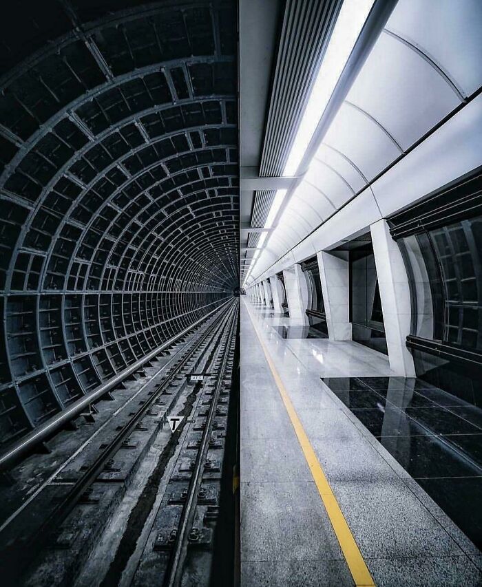 A fascinating find: a split image showing a dark subway tunnel on one side and a brightly lit station on the other.