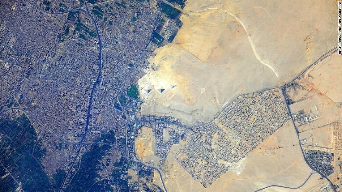 Aerial view of Giza pyramids next to a city and desert, an internet fascinating find.