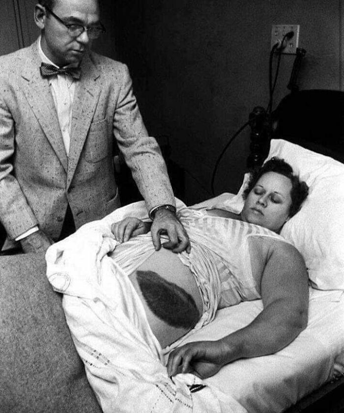 A black and white image of a doctor touching a woman's pregnant belly, showcasing a fascinating find on the internet.