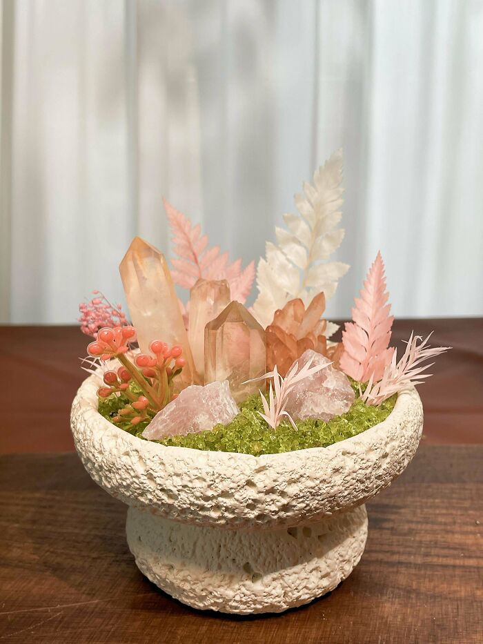 A small decorative bowl filled with various crystals, dried moss, and pink and white foliage, creating a unique handmade project.
