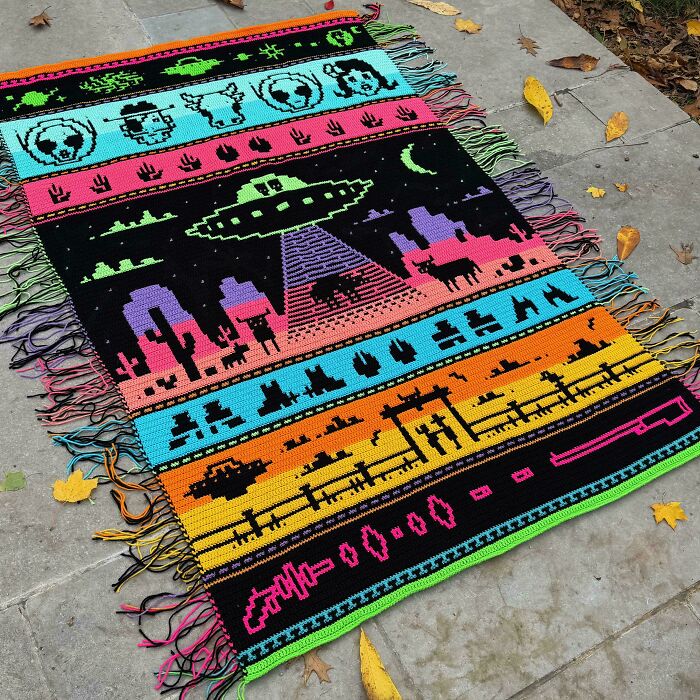 A colorful handmade crochet rug featuring various patterns including a UFO, animals, and pixel art, among many handmade projects.