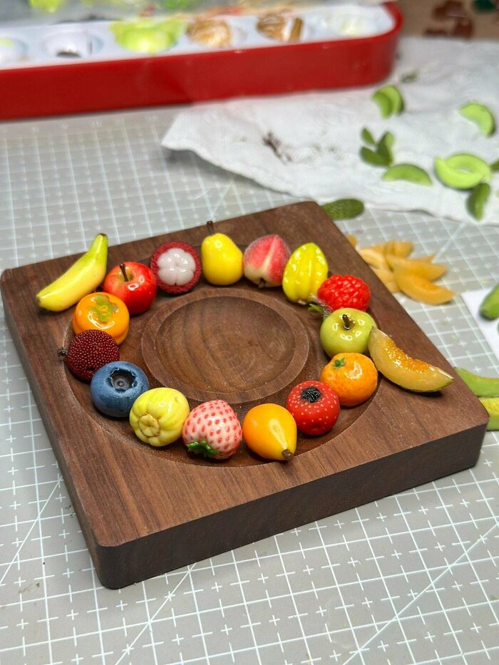 An array of miniature handmade fruit projects arranged in a circle on a wooden board.