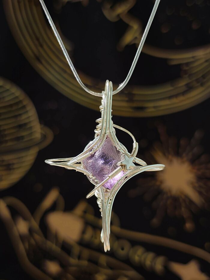 A detailed close-up of a handmade wire-wrapped pendant with a purple crystal, a stunning jaw-dropping project.