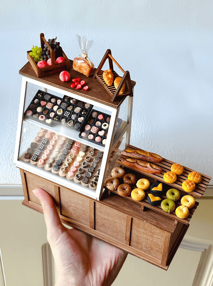 Miniature handmade projects of a bakery stand with tiny pastries, bread, and fruits, jaw-dropping in detail.