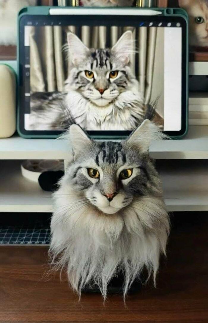 A realistic handmade cat plushie sitting in front of a digital image of a similar cat.
