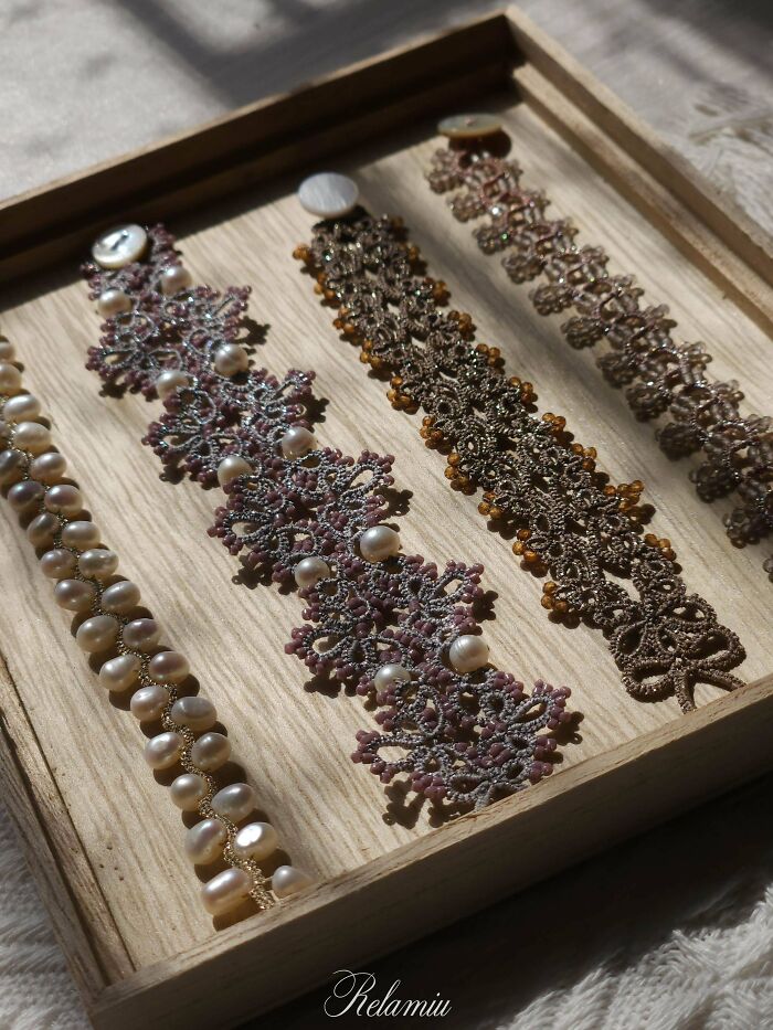 A collection of handmade projects: intricate lace and pearl bracelets displayed on a wooden tray.