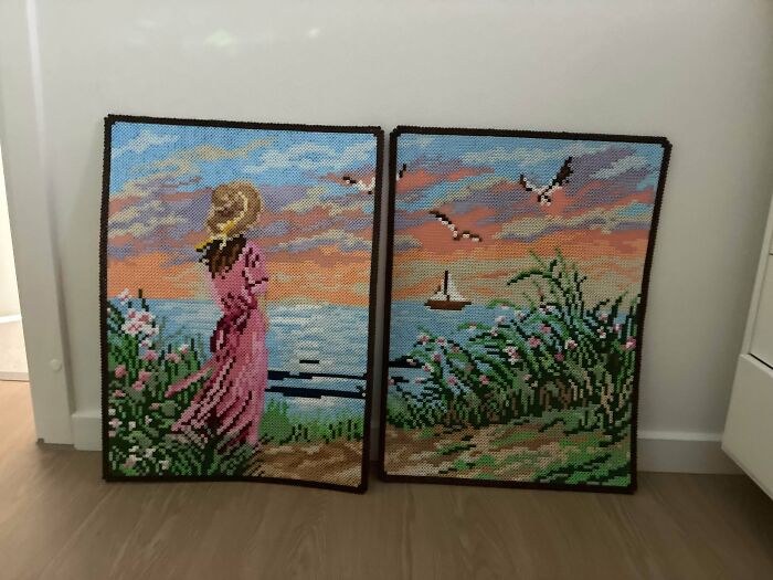 Two framed cross-stitch handmade projects depicting a serene sunset beach scene with a woman and seagulls.