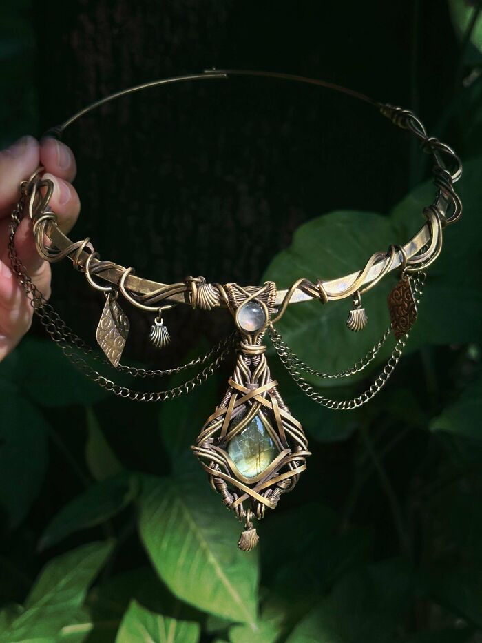 Intricate handmade projects: a wire-wrapped choker necklace featuring a central gemstone and dangling charms.