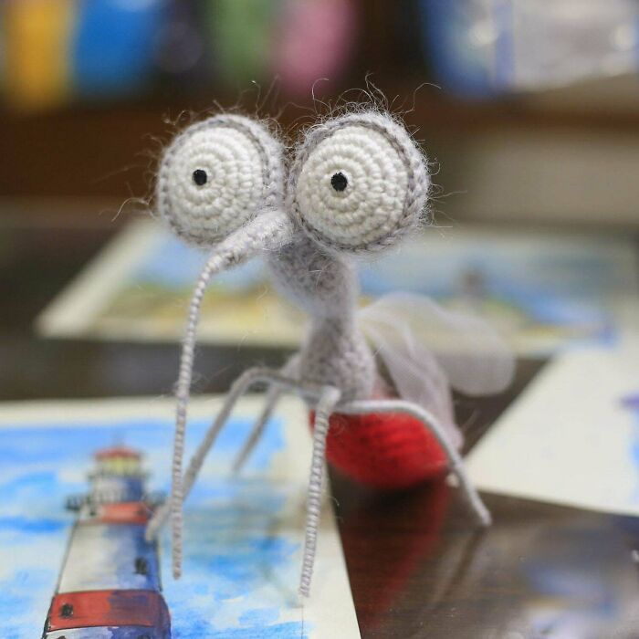 A close-up of a handmade crocheted mosquito with large eyes and a red body, a unique craft project.