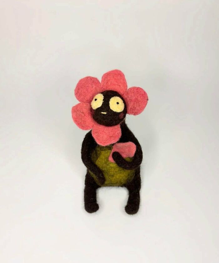 A unique felt handmade project of a dark, squat creature with a pink flower for a head, showcasing unusual handmade projects.