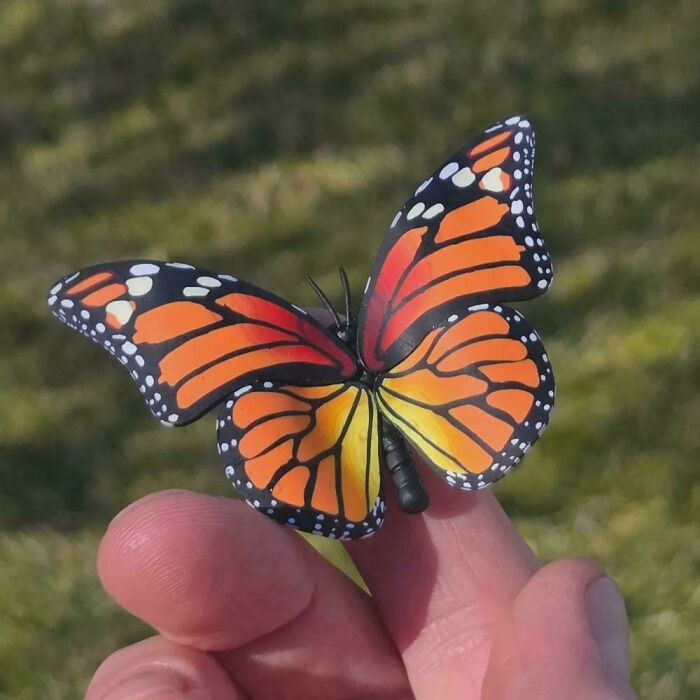 A delicate handmade project of a colorful monarch butterfly perched on a finger, a beautiful representation of handmade projects.