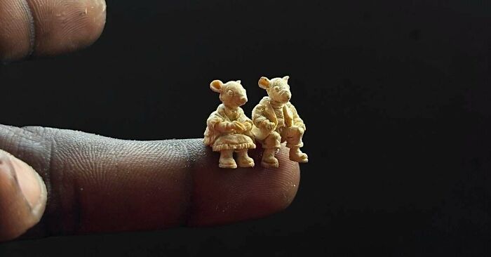 Two tiny handmade mouse figurines, intricately detailed, sitting on a fingertip against a dark background.