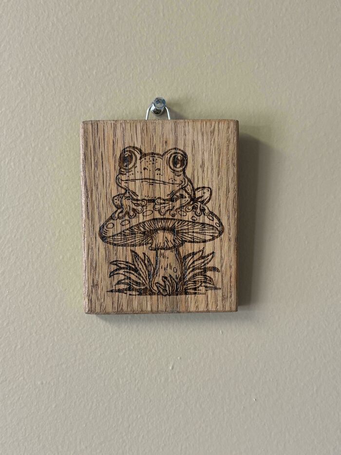 Wood-burned art featuring a frog on a mushroom, a unique handmade project.