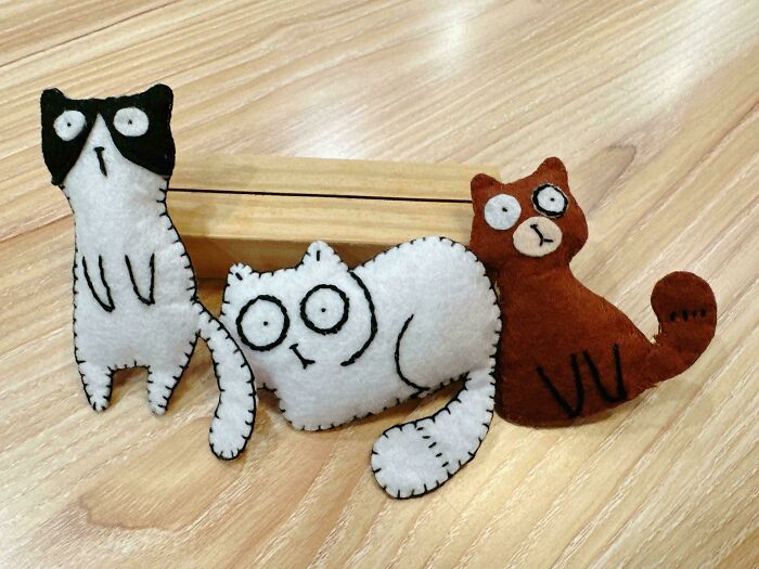Adorable handmade projects: three quirky felt cat toys with stitched details, one black and white, one white, and one brown.