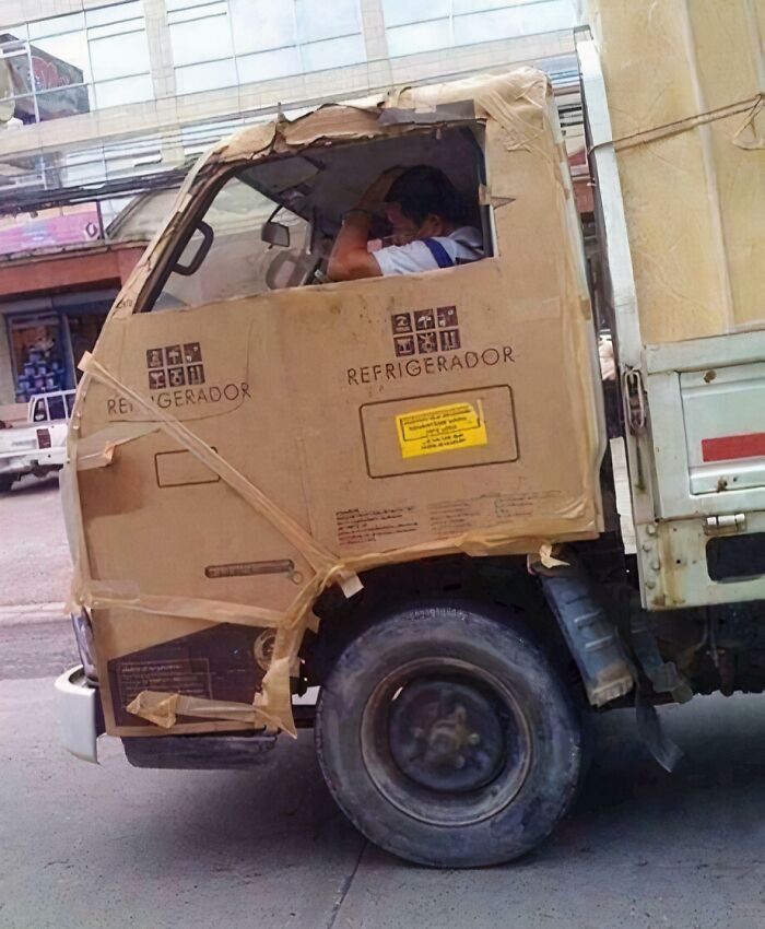 A truck with its cab covered in cardboard boxes, a clever solution for repair using random junk.