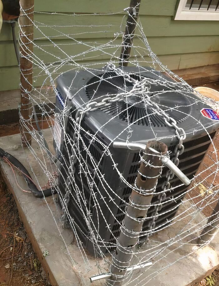 An air conditioning unit wrapped in barbed wire and chains, a clever solution for security.