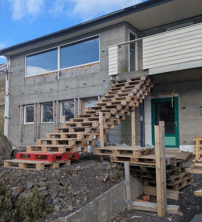A makeshift staircase made from wooden pallets leading up to a house, an example of clever solutions.