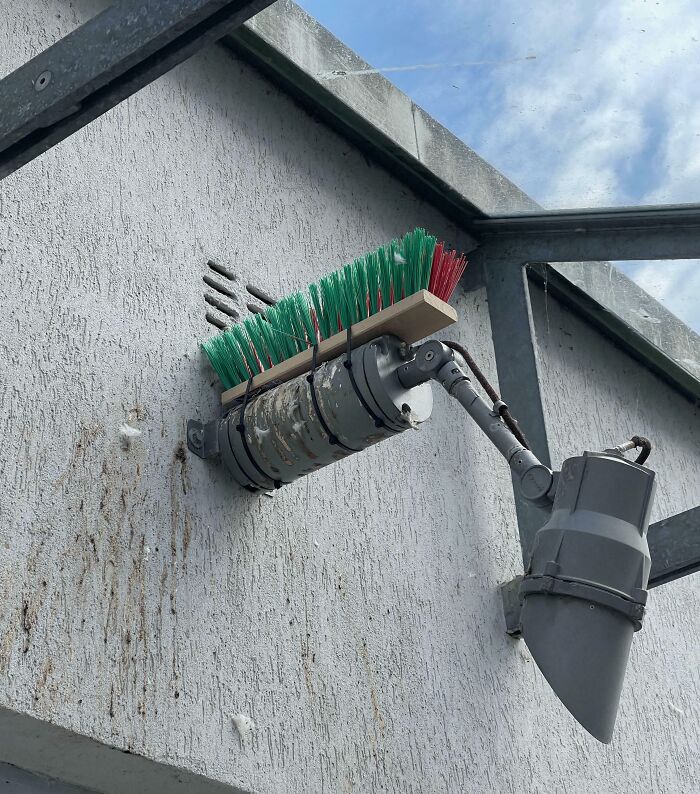 Clever solution: A broom attached to a light fixture for cleaning, demonstrating a clever use of random junk.