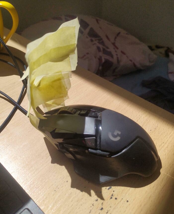 A computer mouse with a piece of yellow tape acting as a fan. A clever solution to keep cool while using junk.