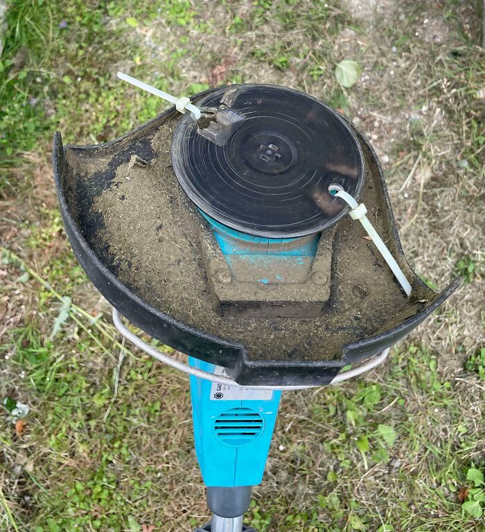 A weed trimmer with white zip ties holding the spool in place, showing clever solutions for junk.