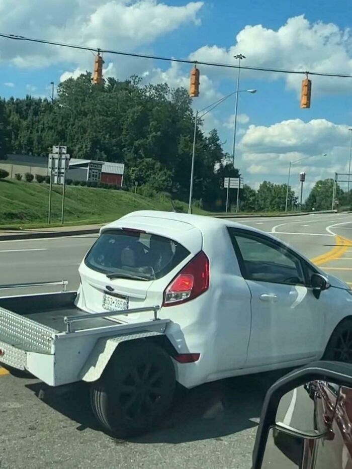 A white car converted into a pickup truck, showcasing people turning random junk into clever solutions.
