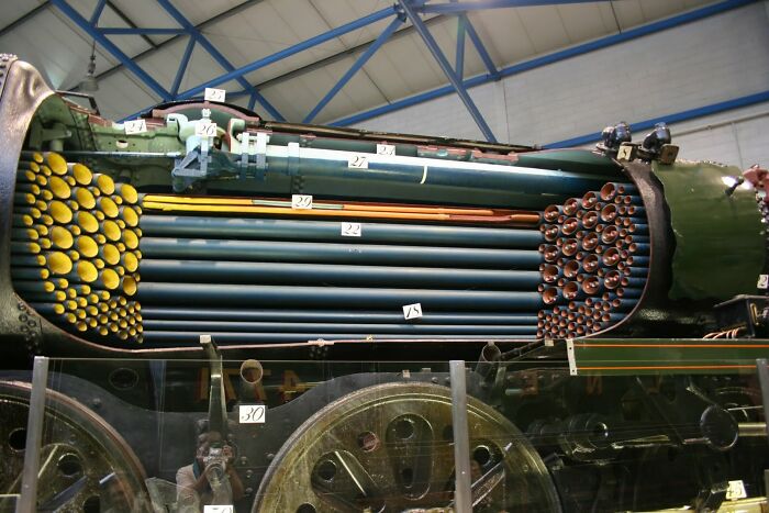 Interesting and surprising photo of a large train engine cut in half, exposing its intricate boiler system.