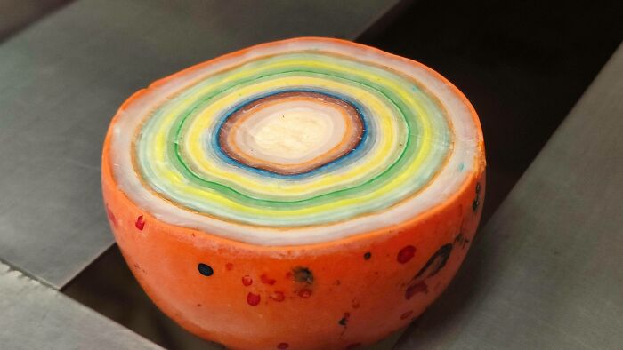 An orange object cut in half, revealing colorful, concentric layers inside, a surprising photo of an object cut in half.