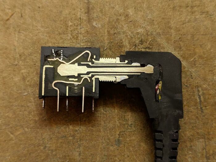 A close-up of an electrical connector cut in half, showing the internal metal contacts and wiring of the object.