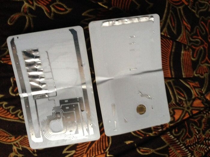 Two objects cut in half, revealing the surprising internal layers of what appears to be a credit card or similar plastic item.