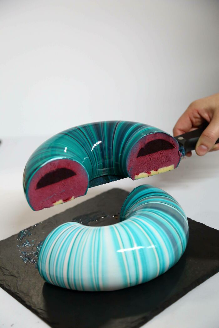 A blue and white striped cake cut in half, revealing a red interior, a surprising photo of an object cut in half.