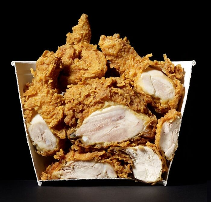 Interesting photo of objects cut in half, revealing the inside of a bucket of fried chicken pieces.