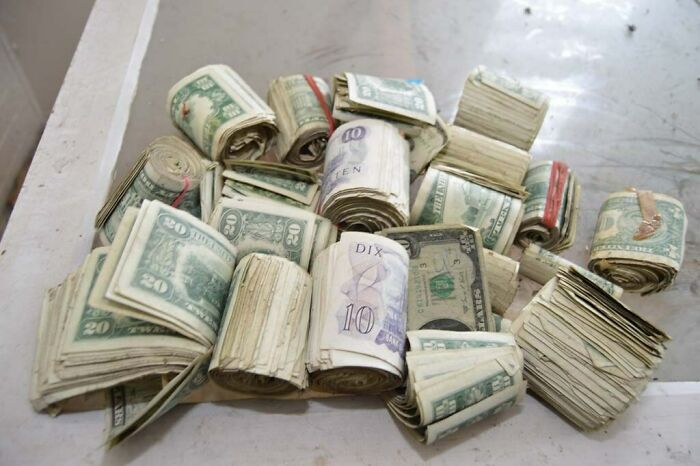 A pile of rolled and stacked cash, including US dollars and other currencies, found while exploring abandoned places, a very unexpected discovery.