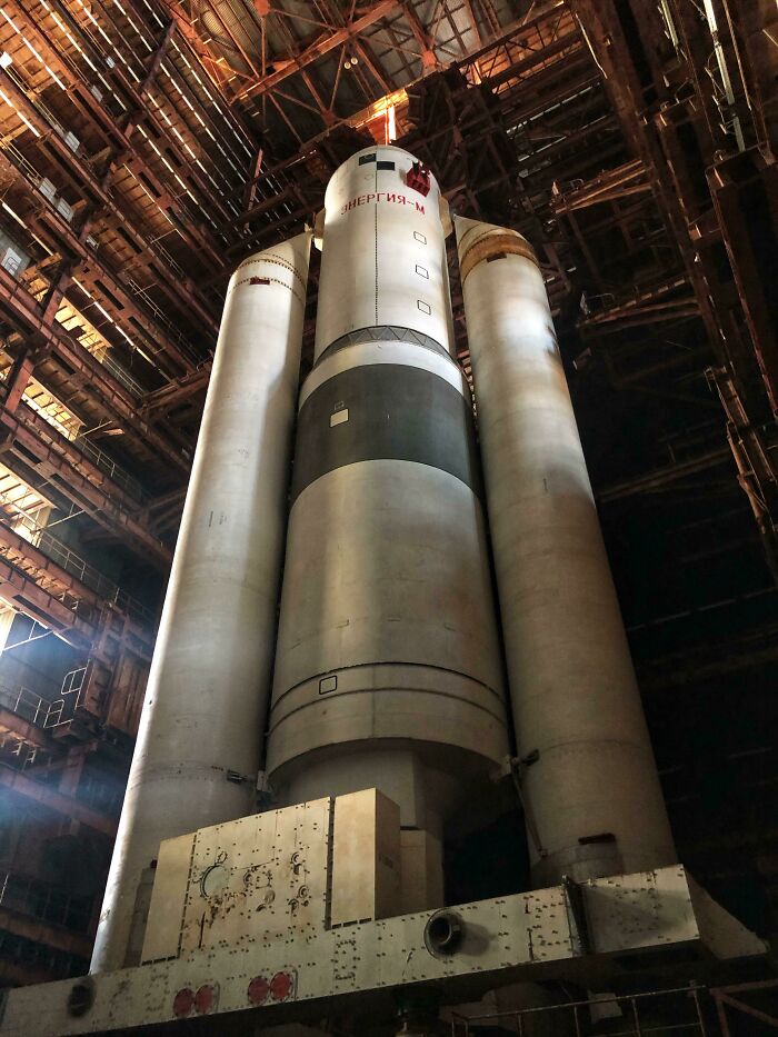 A massive abandoned rocket, part of exploring abandoned places, stands tall inside a large, dilapidated hangar.