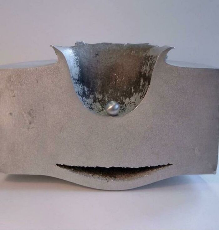 A surprising photo of an object cut in half, revealing a perfectly preserved bullet embedded in a metal block.