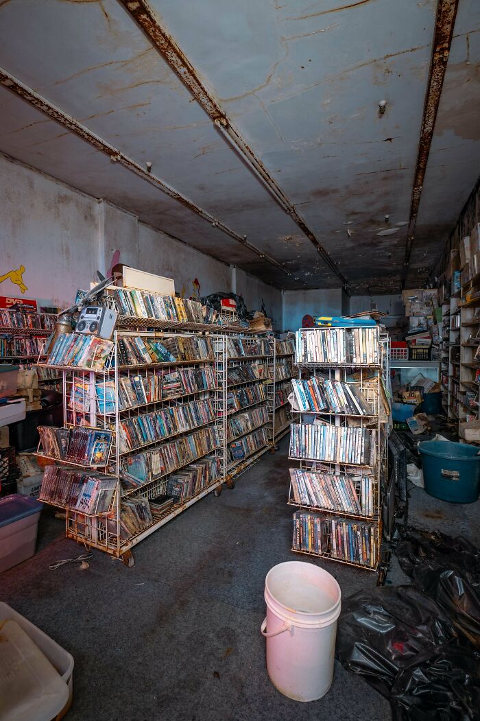 An old, abandoned video store with shelves full of DVDs, exploring abandoned places, showing something unexpected.