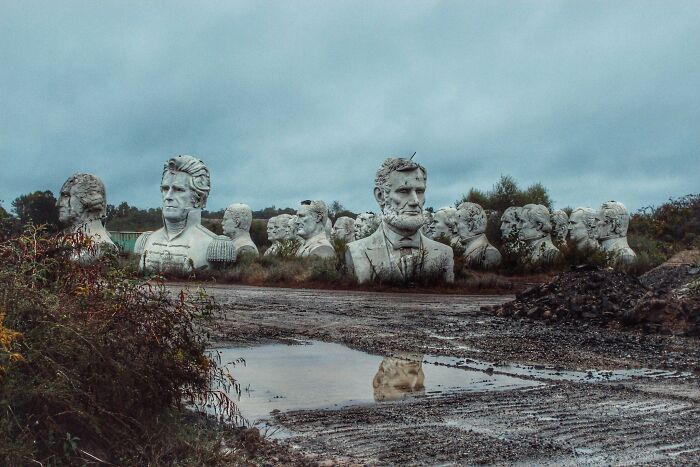 Exploring abandoned places uncovers an eerie field of weathered presidential busts amidst puddles and overgrown brush.