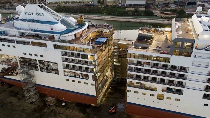 A surprising photo of objects cut in half: a large cruise ship split into two sections in a dry dock for renovation.