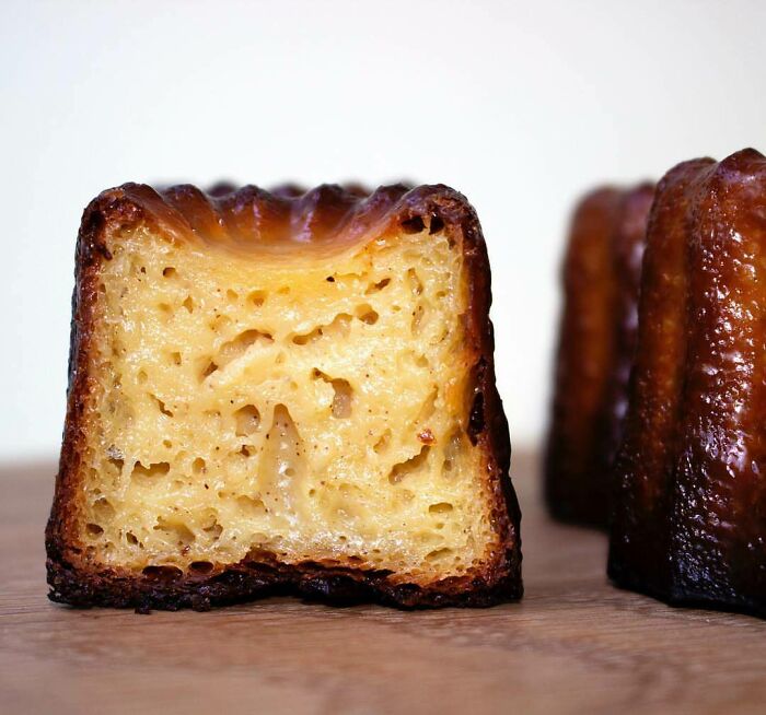 A canelé pastry cut in half, showcasing its custardy interior with small air pockets, surprising photos of objects.