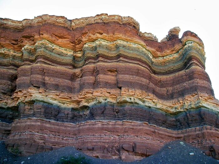 Interesting and surprising photos of a stunning rock formation, naturally cut in half, displaying colorful geological layers.