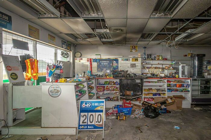 Exploring abandoned places: an old, ransacked convenience store with debris and fallen ceiling tiles.