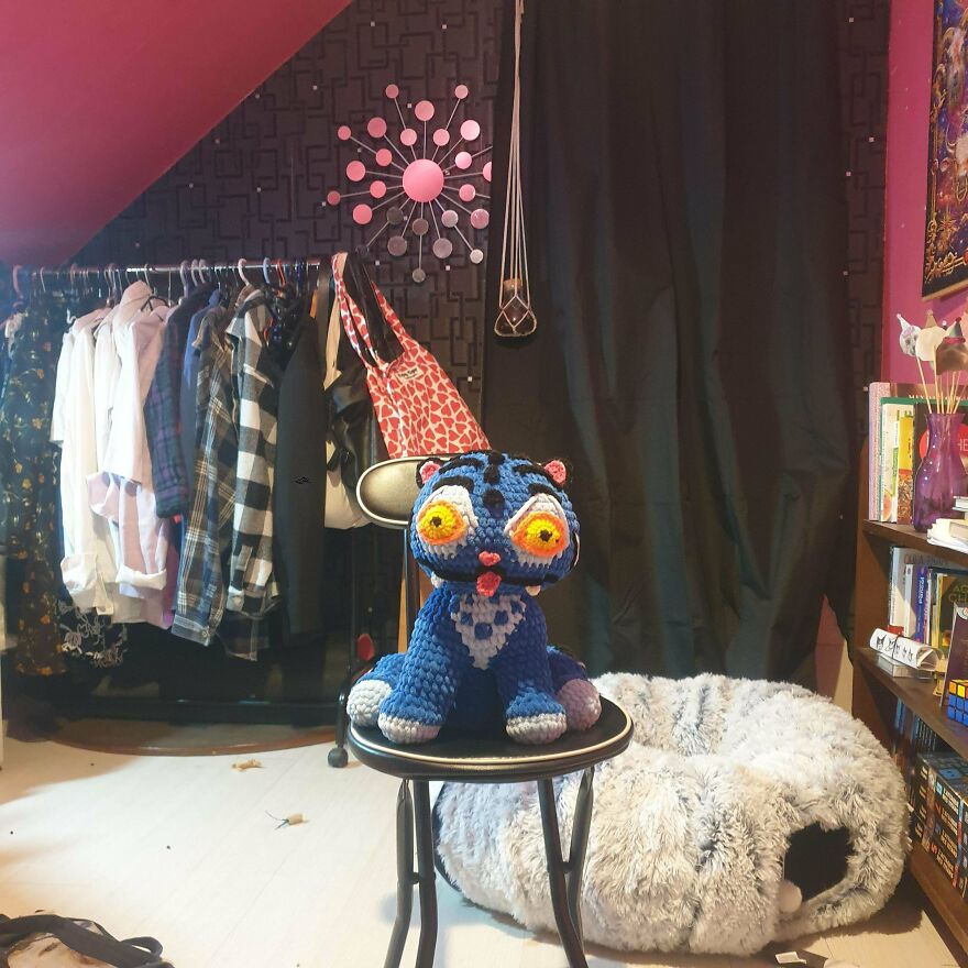 A vibrant blue crochet creation monster with large eyes sitting on a stool, a quirky craft project.