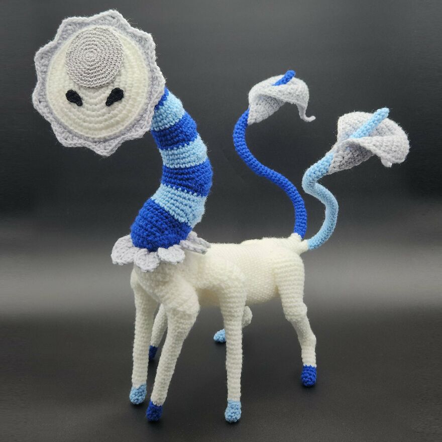 A whimsical crochet creation creature resembling a giraffe with a striped neck and calla lily accents, a unique craft project.