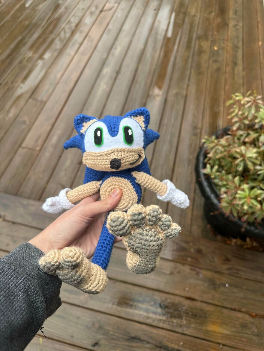 A hand holding a blue crochet creation resembling Sonic the Hedgehog, a unique crochet project.