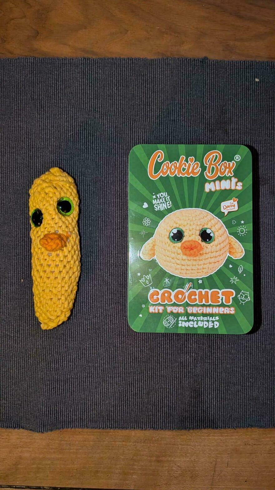 A crochet creation of a yellow chick next to its Cookie Box Minis crochet kit for beginners.