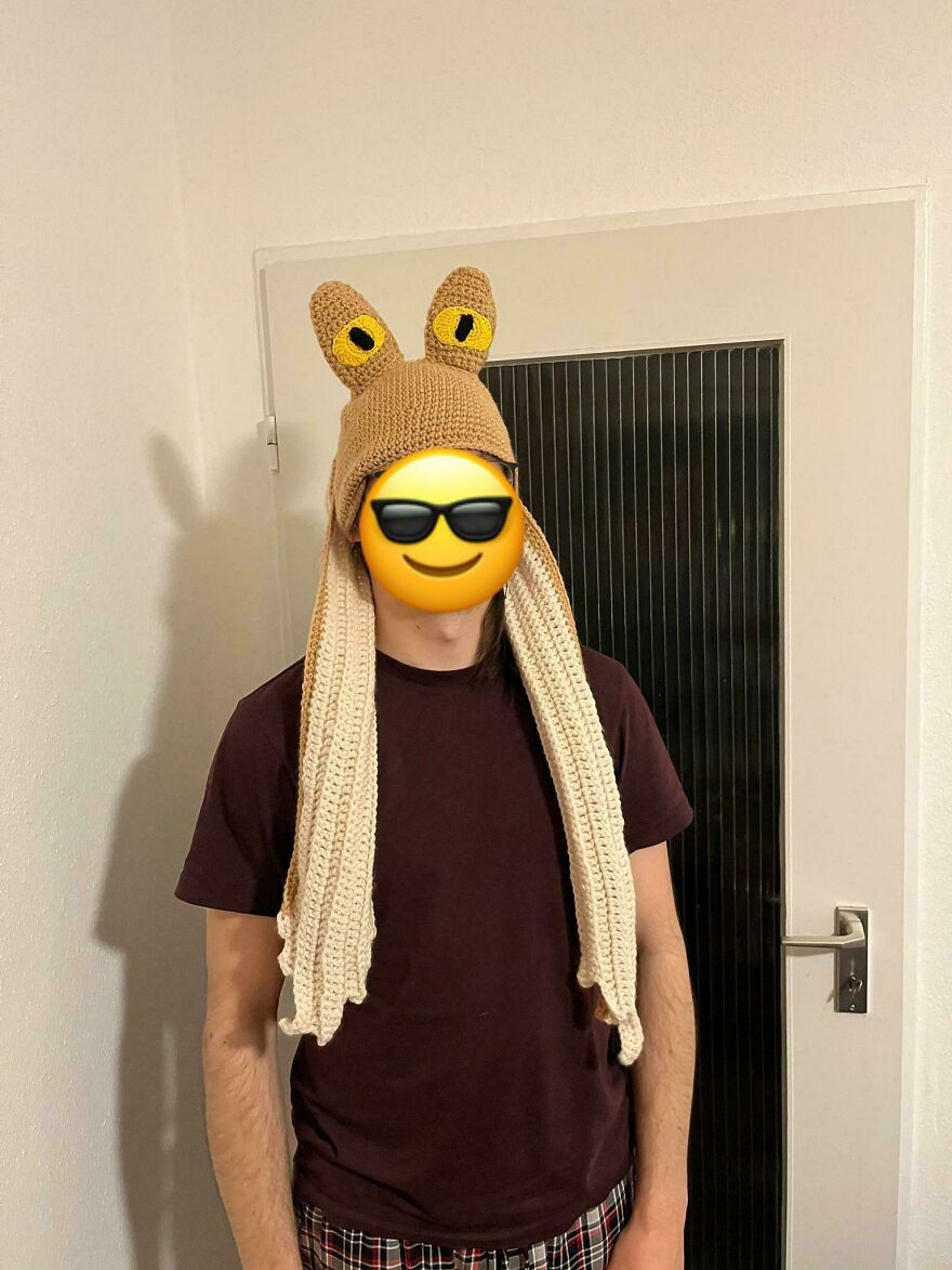 A person wearing a brown and yellow crochet hat resembling a character from Star Wars.