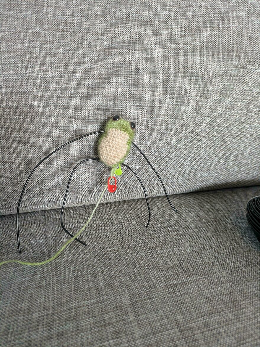 A small, green crochet creation of a frog with wires for legs, symbolizing a craft project that might not have turned out as intended.