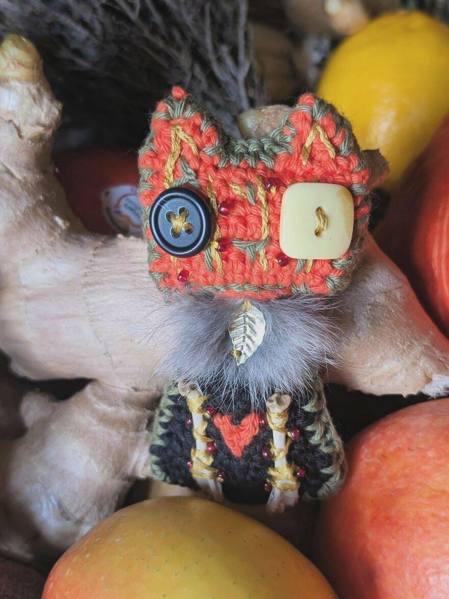 An elaborate orange, green, and black crochet creation adorned with buttons and fur, a detailed craft project.