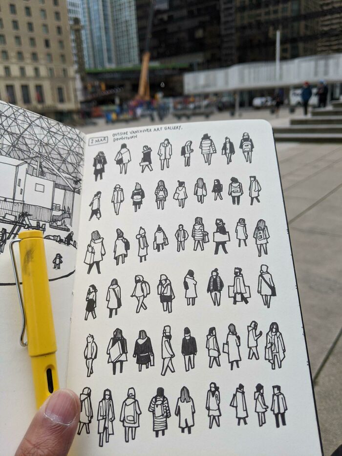 A hand holding a sketchbook filled with wholesome images of drawn figures outside the Vancouver Art Gallery.