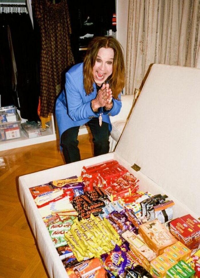 Ozzy Osbourne smiling excitedly with wholesome images of a large chest full of various candies and chocolates.