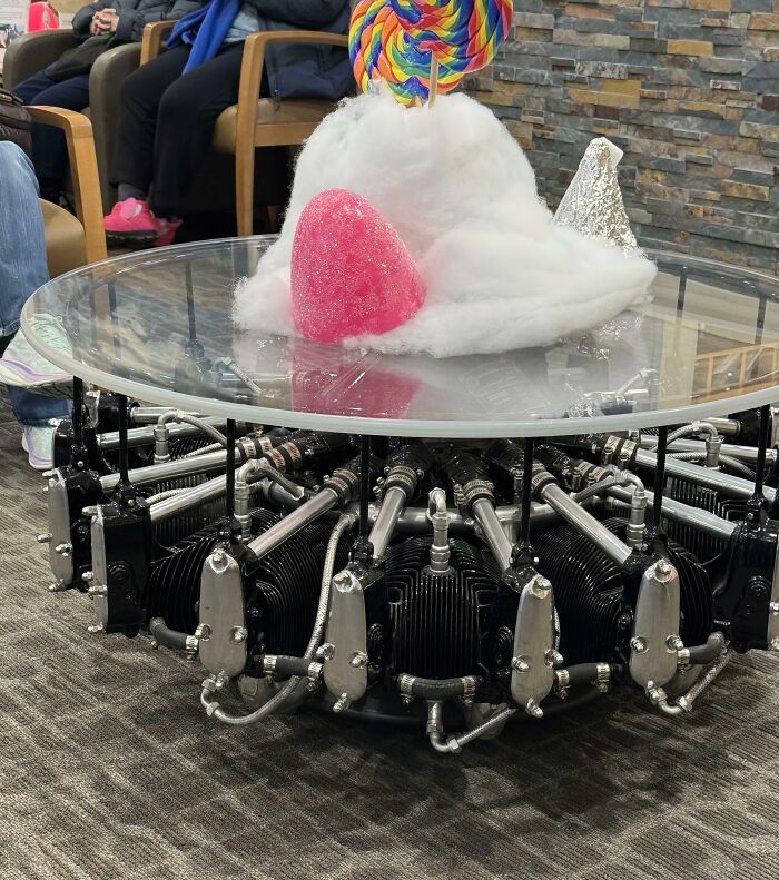 A coffee table made from an airplane engine, displaying baffling images of a giant lollipop, cotton candy, and a gummy.